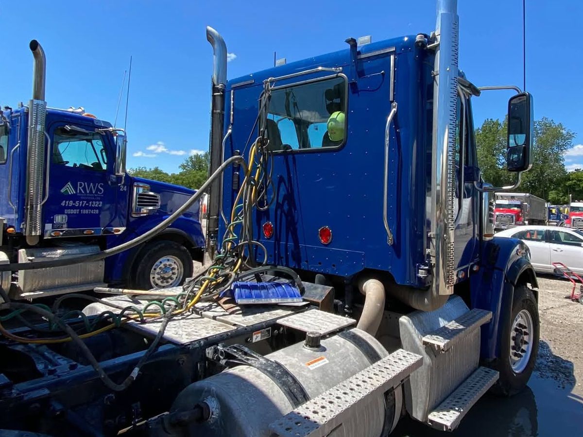 Clean glossy blue tractor cab with a bright aluminum fuel tank and step plates.