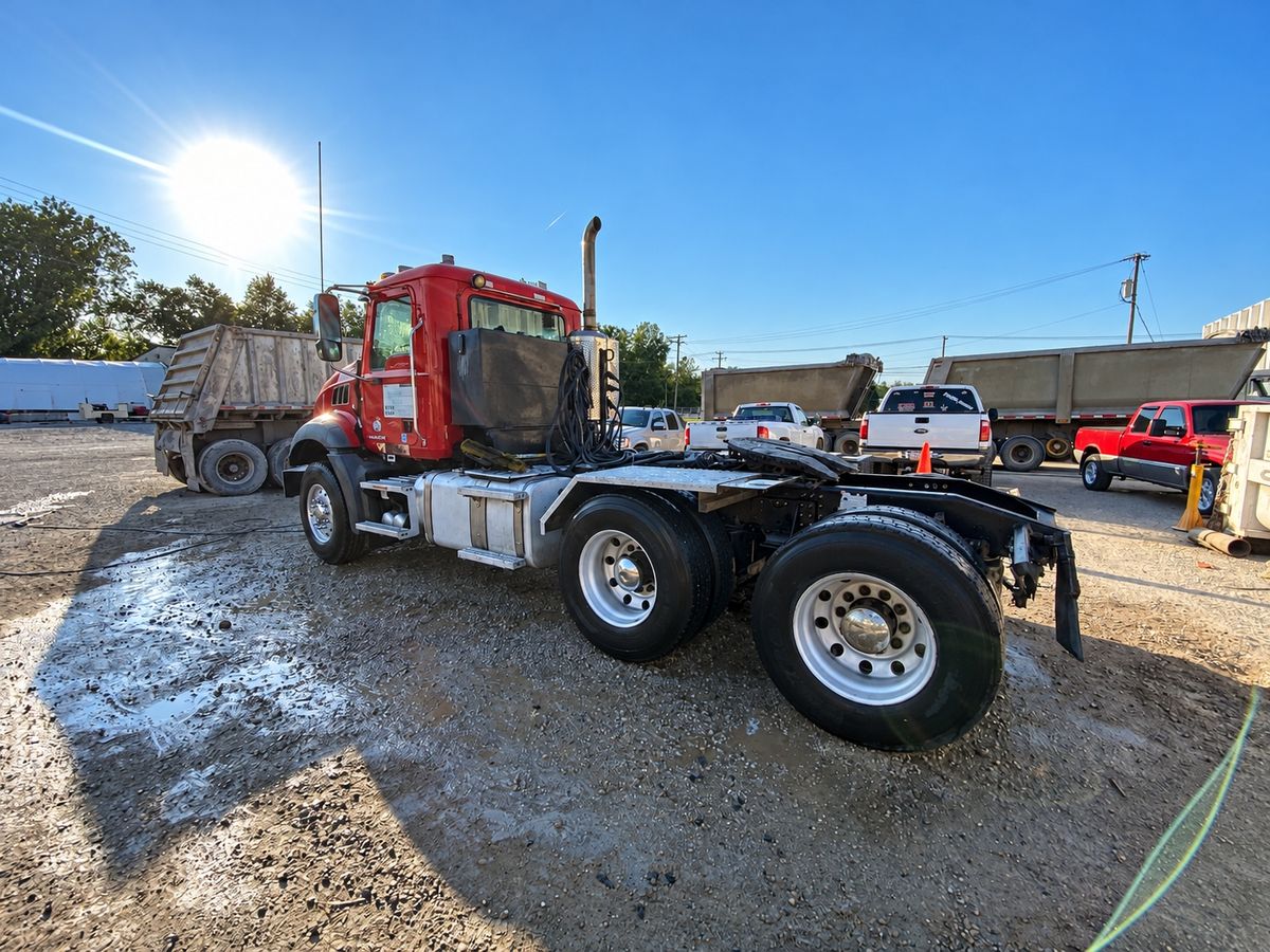 Red Mack tractor from the rear quarter with a bright fuel tank and polished rear wheels in the low sun.