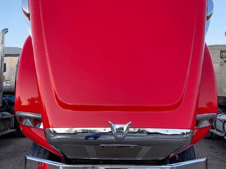 Red truck with the hood raised, glossy deep red with a bright chrome bumper.