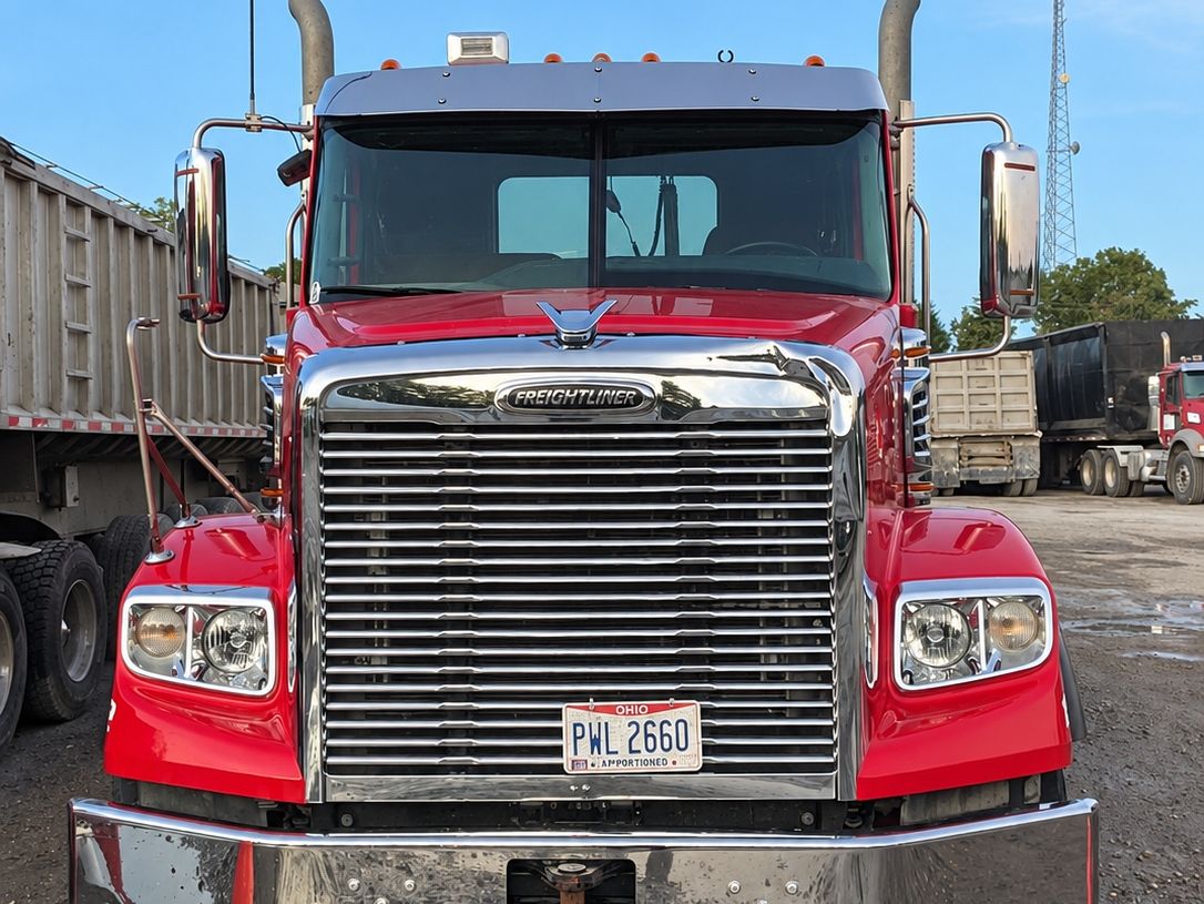 Red Freightliner from the front with bright fenders and a clean chrome grille.