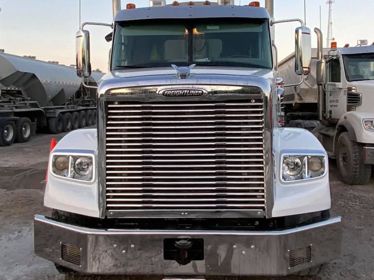 White Freightliner from the front with clean fenders and a bright chrome grille and bumper.