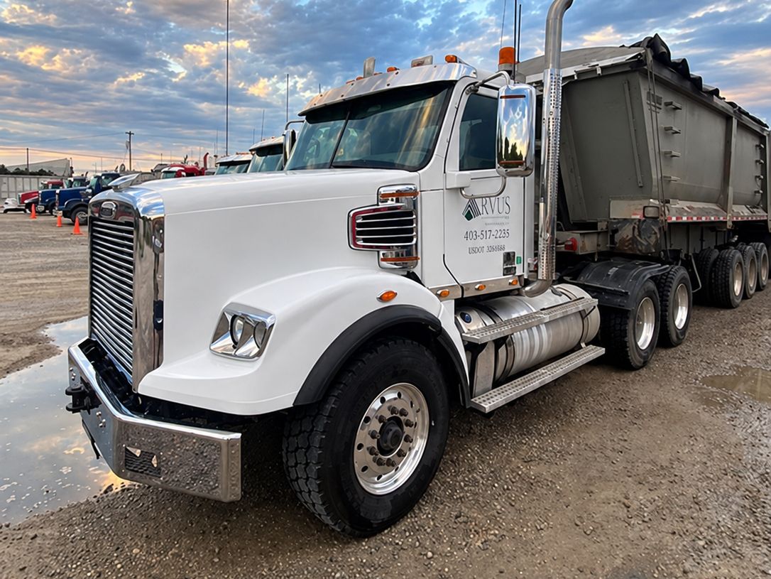 Clean white tractor numbered 17 with a polished wheel and chrome bumper and a dump trailer behind it at dusk.