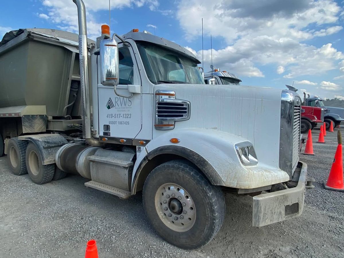 White Freightliner with gray road film over the hood, fender and bumper.