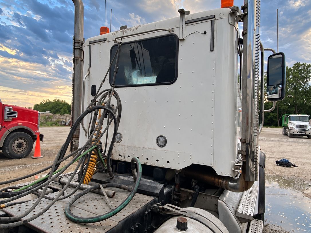 Clean white tractor cab from behind with tall polished stacks and a bright fuel tank.