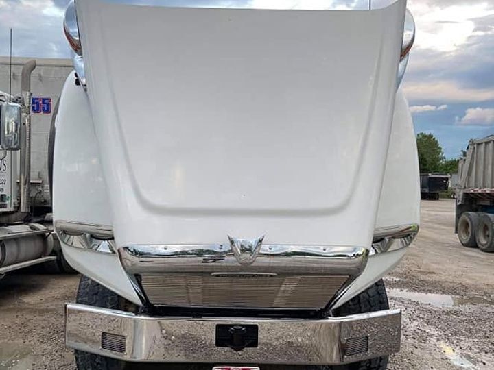 White truck with its hood raised, the hood bright white above a polished chrome bumper.