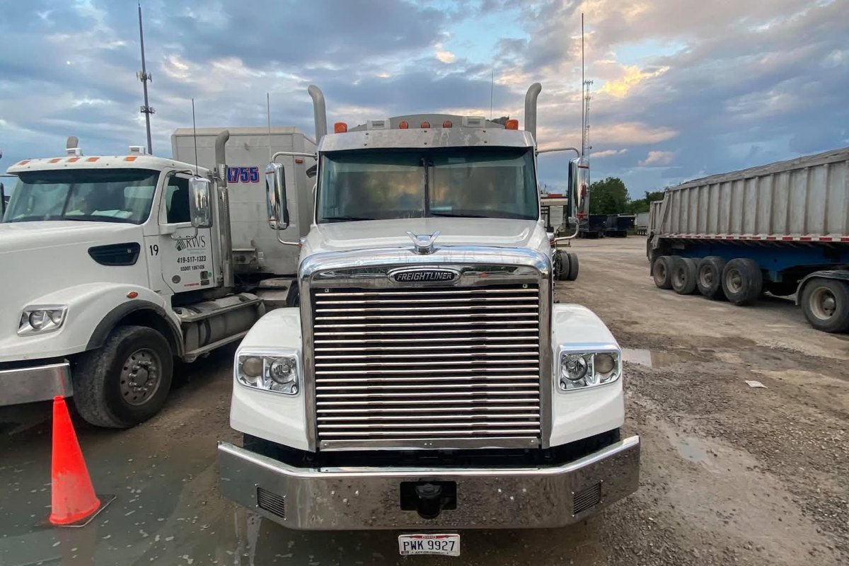 White Freightliner seen from the front with clean paint and a bright chrome bumper.