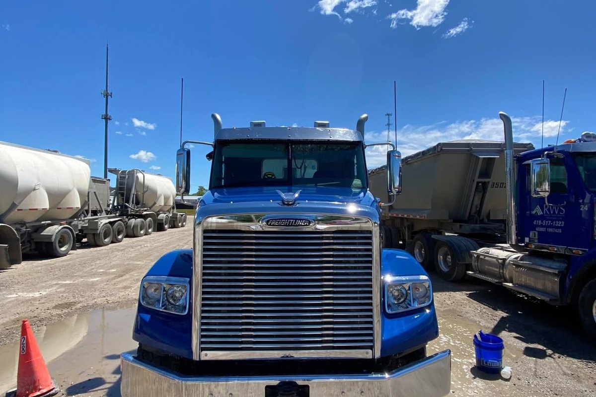 Head-on view of a clean blue Freightliner tractor with glossy blue fenders and a bright chrome grille and bumper.