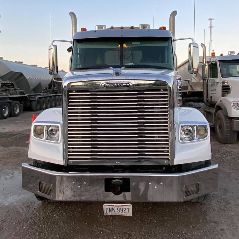 Clean white tractor from the front with a chrome bumper and grille between two traffic cones.